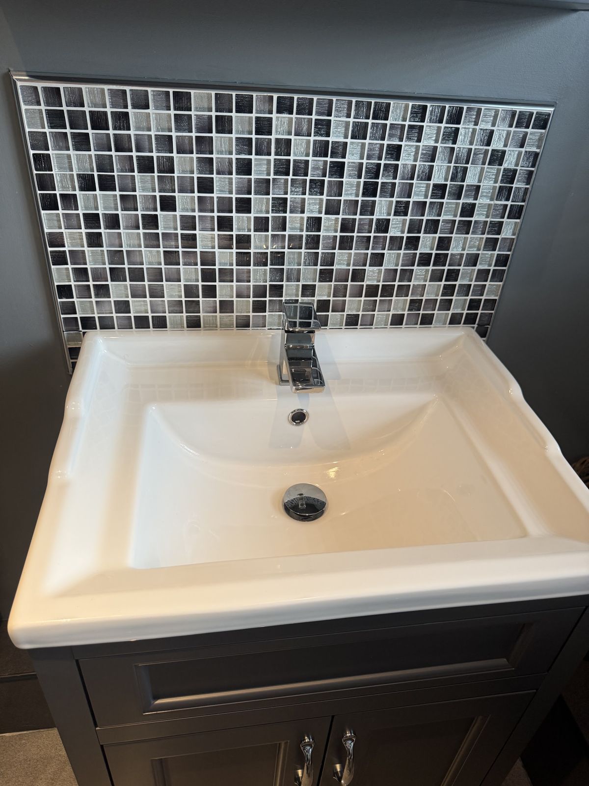 Basin on a dark vanity unit with a mosaic tile splashback